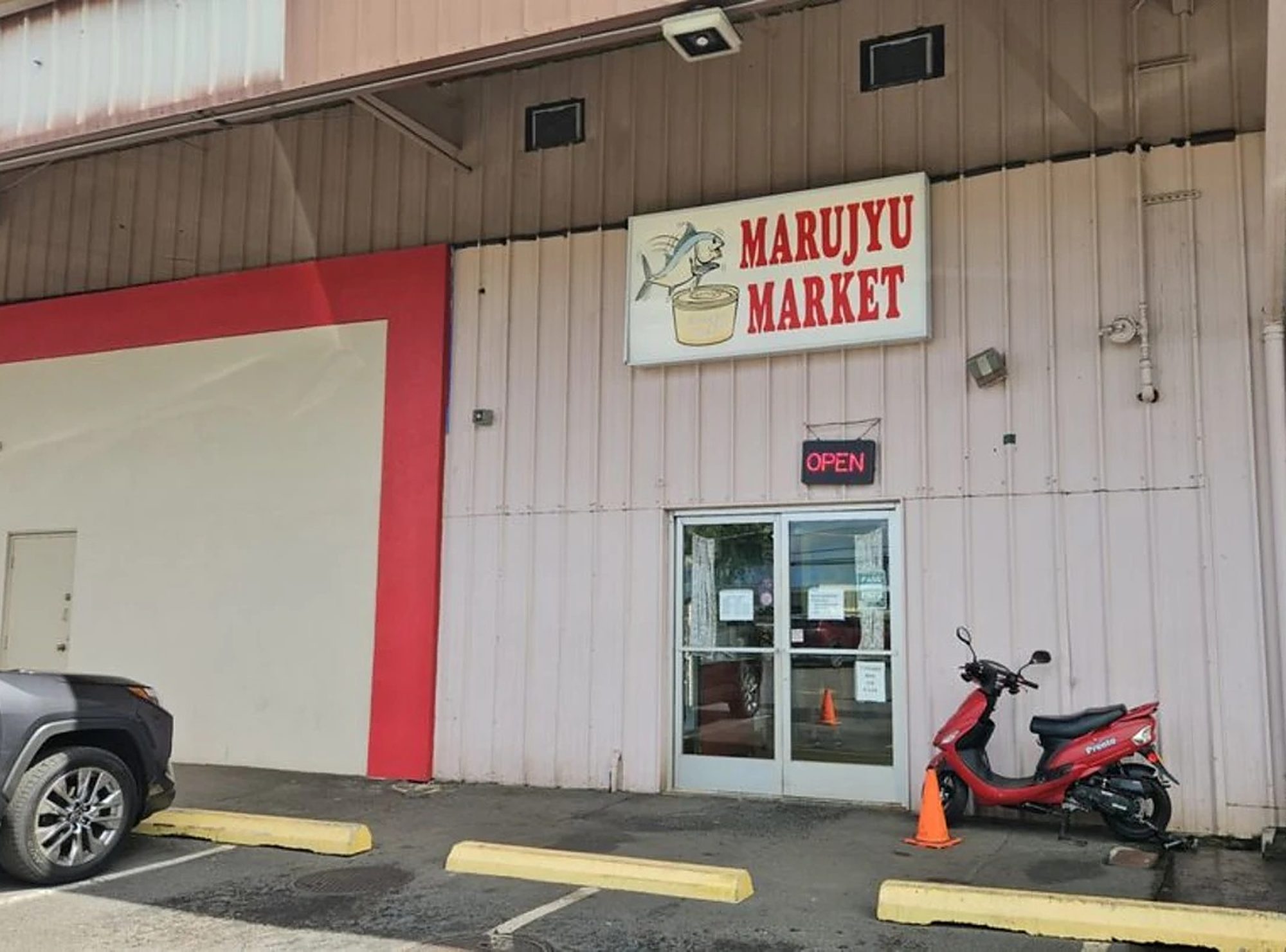 The front of Marujyu Market: their sign over the door, the OPEN sign lit and a scooter parked outside